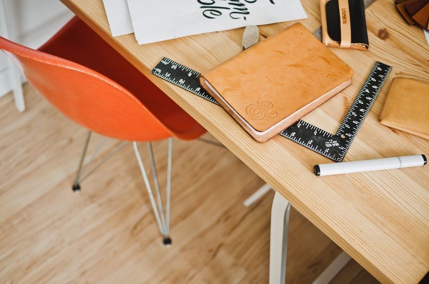 A leather notebook and a pen on a wooden working table